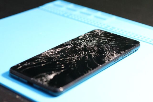 Handy mit gesprungenem Display auf der Reparaturmatte — Display Reparatur Düsseldorf