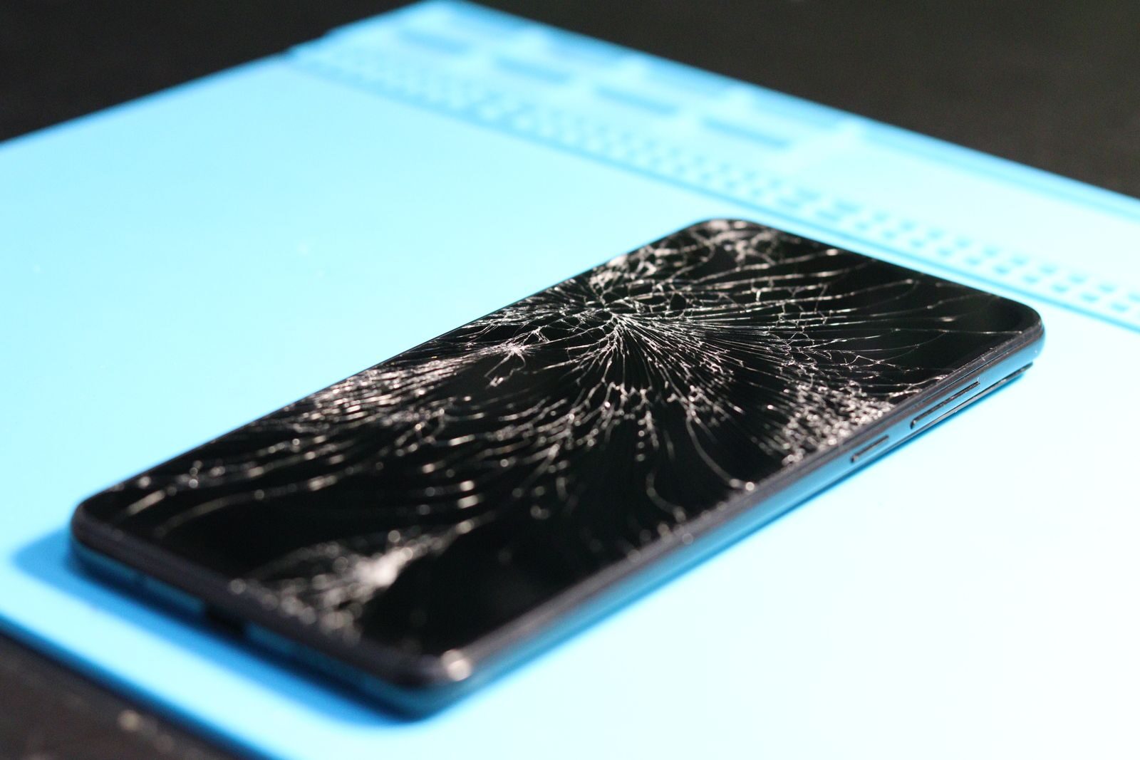 Handy mit gesprungenem Display auf der Reparaturmatte — Display Reparatur Düsseldorf