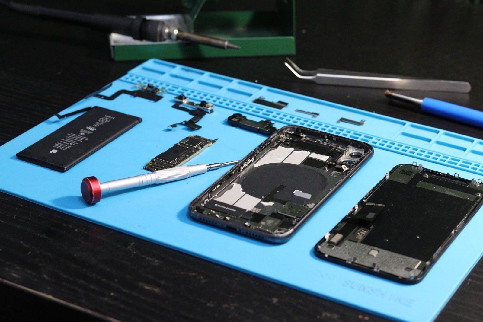 Geöffnetes iPhone mit Werkzeug auf der Reparaturmatte — iPhone Reparatur Düsseldorf