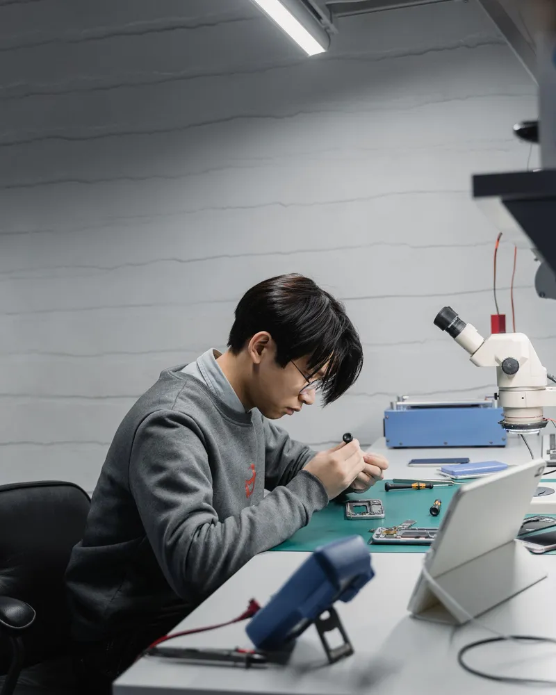 Ein Techniker arbeitet an einem geöffneten Handy am Reparaturplatz